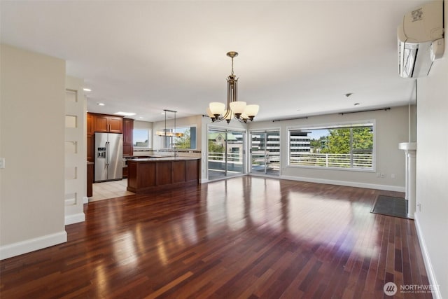 unfurnished dining area featuring a chandelier, an AC wall unit, baseboards, wood finished floors, and recessed lighting