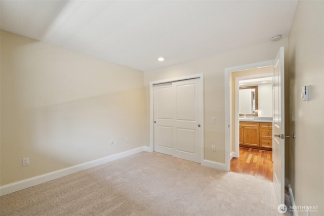 unfurnished bedroom featuring light carpet, baseboards, recessed lighting, and a closet