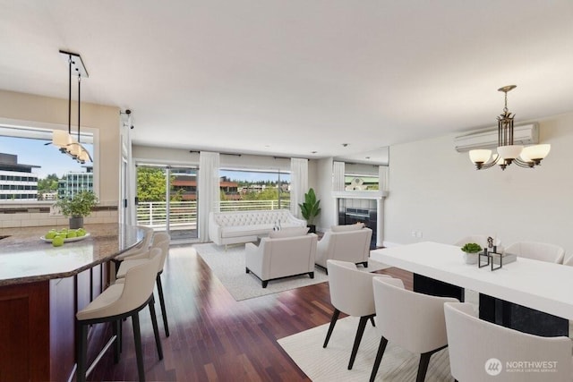 dining area with a chandelier, an AC wall unit, wood finished floors, and a fireplace