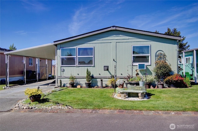 manufactured / mobile home with driveway, a carport, and a front yard