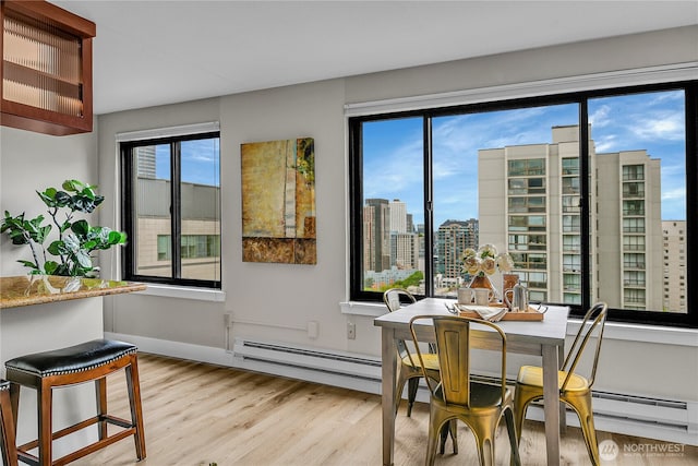 1105 Spring St Unit 1306, Seattle, WA 98104 - dining space featuring baseboard heating, light wood finished floors, a view of city, and baseboards