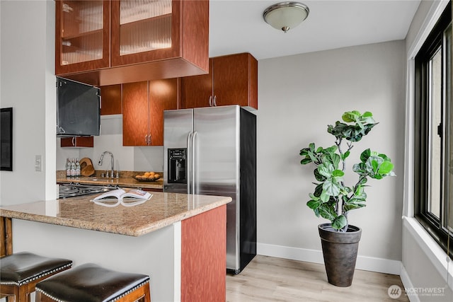 1105 Spring St Unit 1306, Seattle, WA 98104 - kitchen featuring stainless steel fridge, light wood-style floors, baseboards, light stone countertops, and a sink