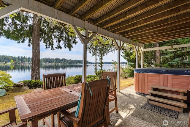 view of patio / terrace featuring a hot tub, a water view, and outdoor dining space