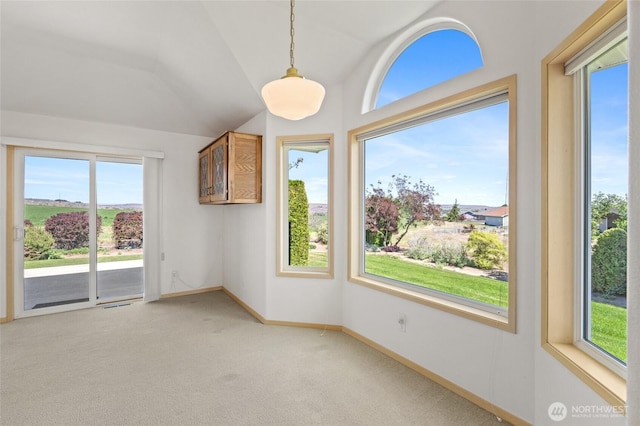 empty room with light colored carpet, a wealth of natural light, vaulted ceiling, and baseboards