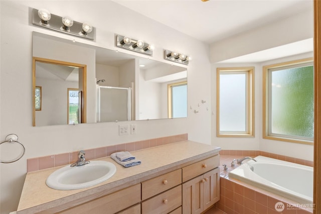 bathroom featuring vanity, a bath, a shower stall, and plenty of natural light