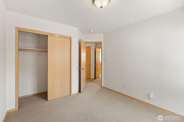 unfurnished bedroom with baseboards, a closet, and light colored carpet
