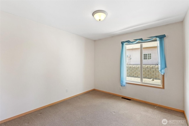 empty room featuring baseboards, light carpet, and visible vents
