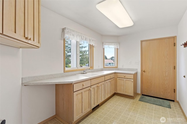 kitchen with a sink, light floors, light brown cabinetry, and light countertops