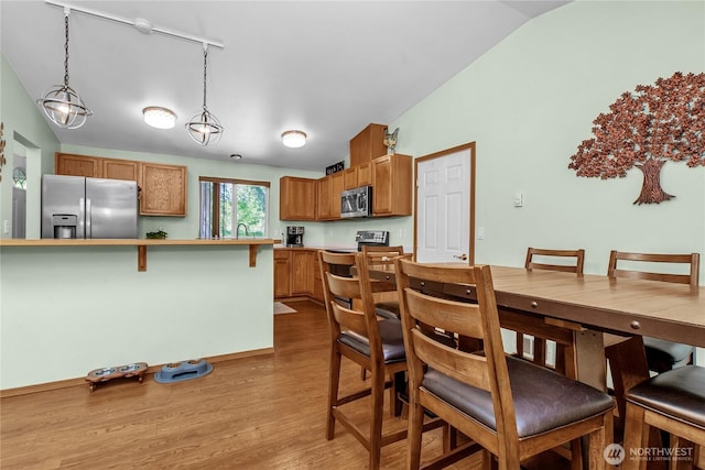 dining area featuring light wood finished floors and lofted ceiling