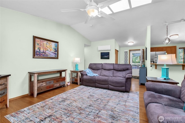 living area with a wall mounted AC, ceiling fan, wood finished floors, vaulted ceiling, and a skylight
