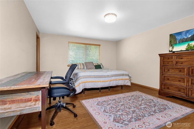 bedroom featuring an office area, wood finished floors, and baseboards