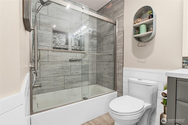 full bathroom with vanity, combined bath / shower with glass door, toilet, and wood finished floors
