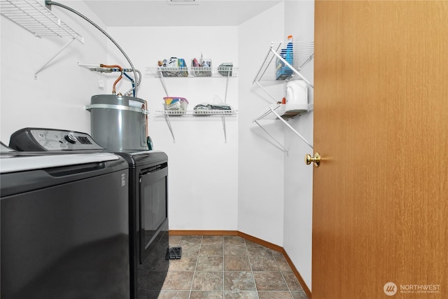 washroom with washer and dryer, baseboards, stone finish flooring, and strapped water heater