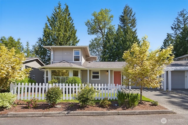 traditional-style house featuring a garage, fence private yard, and aphalt driveway