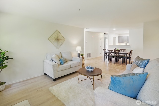 living room featuring light wood finished floors, visible vents, baseboards, and recessed lighting