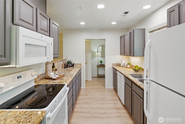 kitchen featuring light wood finished floors, visible vents, light stone countertops, white appliances, and recessed lighting