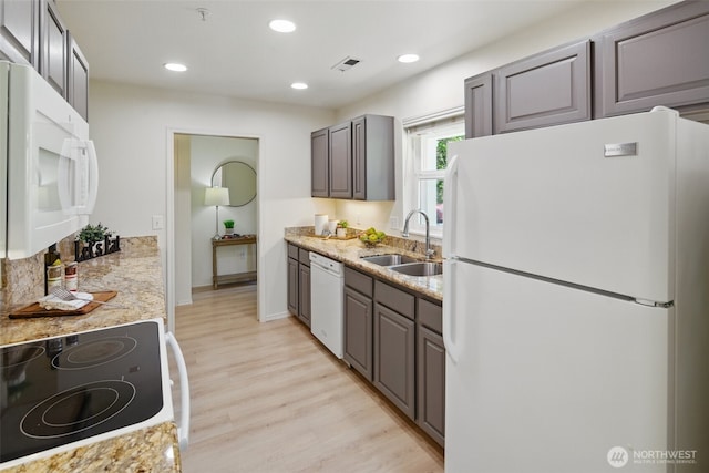 kitchen featuring light wood finished floors, a sink, visible vents, white appliances, and recessed lighting