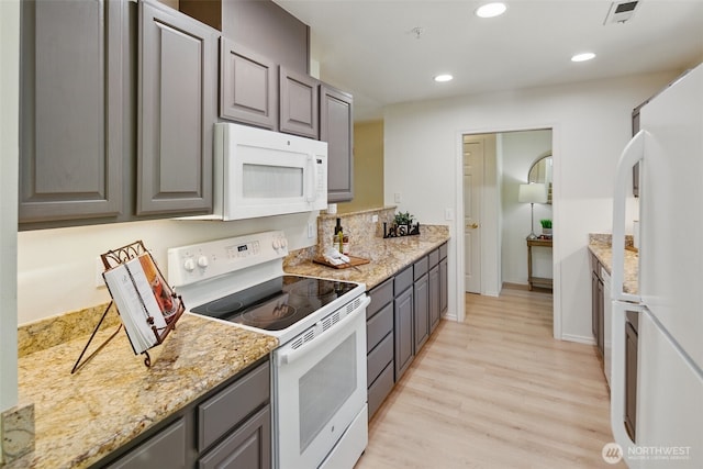 kitchen with light wood finished floors, white appliances, gray cabinets, and visible vents