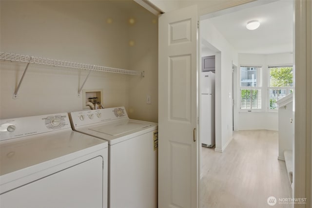 clothes washing area with laundry area, light wood-style flooring, baseboards, and independent washer and dryer