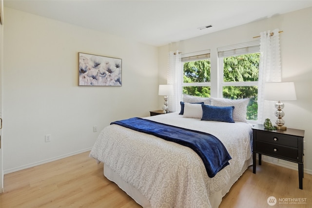 bedroom with baseboards, light wood-style floors, and visible vents