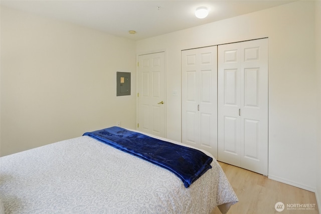 bedroom featuring electric panel, light wood finished floors, and a closet
