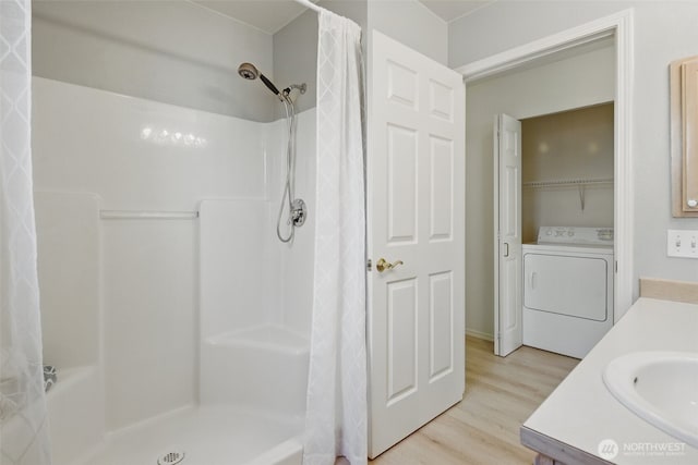 bathroom with a shower with shower curtain, wood finished floors, vanity, and washer / clothes dryer