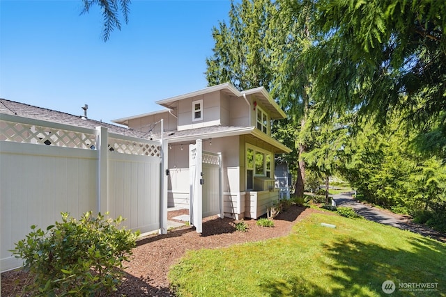 view of side of property with a lawn, fence, and a gate