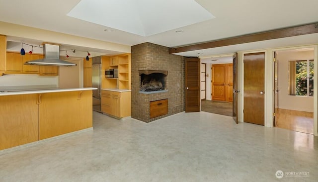 kitchen featuring light floors, stainless steel microwave, island exhaust hood, and a fireplace