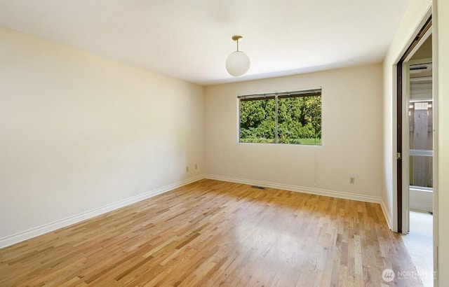 empty room featuring baseboards, light wood-type flooring, and visible vents