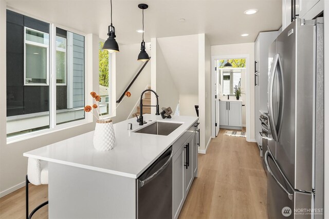kitchen with appliances with stainless steel finishes, a sink, light wood-type flooring, light countertops, and recessed lighting