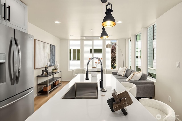 kitchen featuring stainless steel fridge with ice dispenser, a sink, light wood-type flooring, open floor plan, and recessed lighting