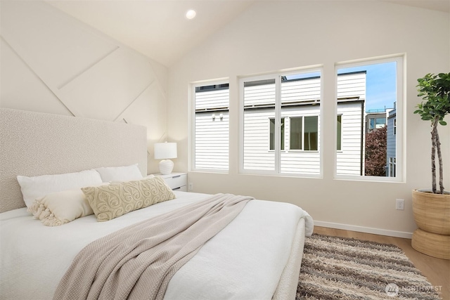 bedroom featuring multiple windows, vaulted ceiling, wood finished floors, and baseboards
