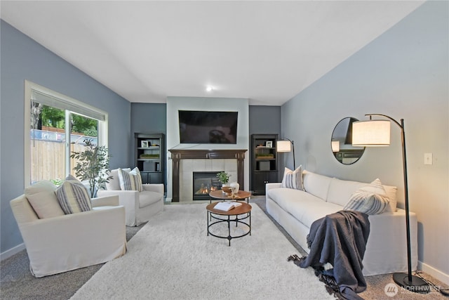 living area with carpet flooring, baseboards, and a tile fireplace