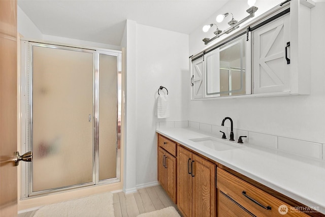 bathroom featuring a stall shower, vanity, wood finished floors, and baseboards