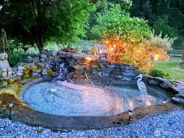 view of swimming pool featuring a garden pond and an outdoor fire pit