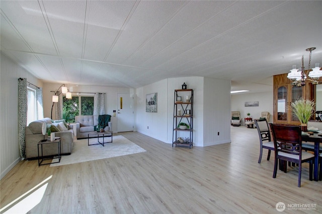 living area with a notable chandelier, baseboards, and wood finished floors