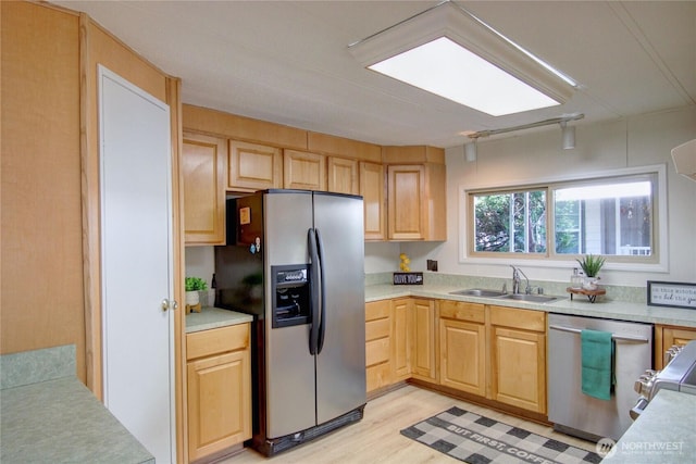 kitchen featuring a sink, stainless steel appliances, light wood-style flooring, light countertops, and light brown cabinets