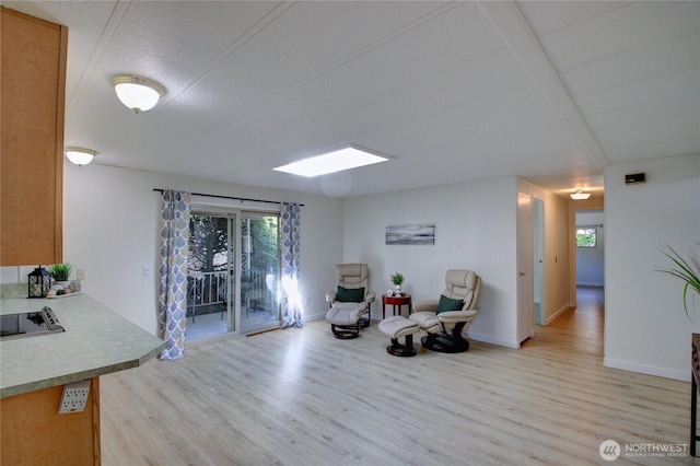 living area featuring a wealth of natural light, light wood-style flooring, and baseboards