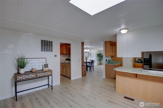 kitchen with light wood-style flooring, visible vents, and stainless steel refrigerator with ice dispenser