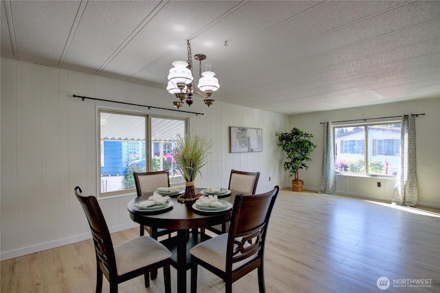 dining room with a textured ceiling, light wood-style flooring, and a notable chandelier
