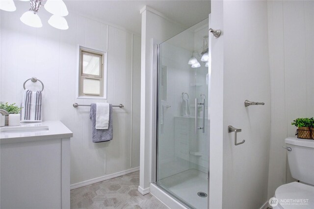 bathroom with vanity, toilet, a shower stall, and a notable chandelier