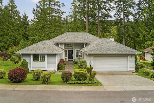view of front facade with an attached garage, concrete driveway, roof with shingles, and a front yard