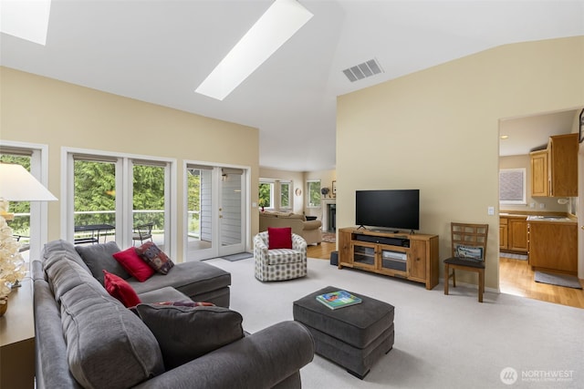 living area with a skylight, light carpet, and high vaulted ceiling