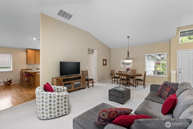 living room featuring vaulted ceiling, baseboards, and light colored carpet