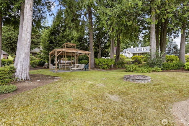 view of grassy yard with a gazebo, view of scattered trees, and a fire pit