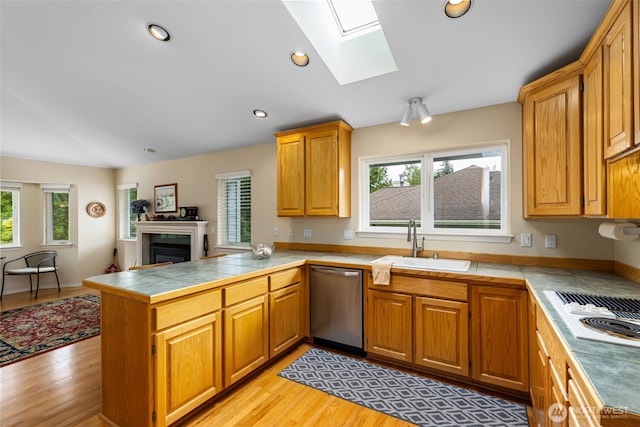 kitchen featuring stainless steel dishwasher, a sink, a peninsula, white electric stovetop, and a fireplace