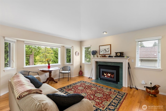 living room featuring healthy amount of natural light, a tiled fireplace, and wood finished floors