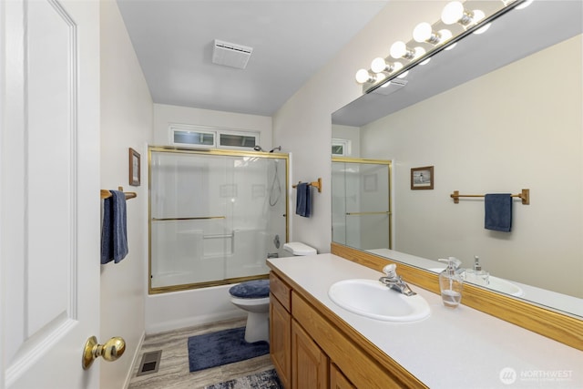 full bath with toilet, vanity, combined bath / shower with glass door, wood finished floors, and baseboards