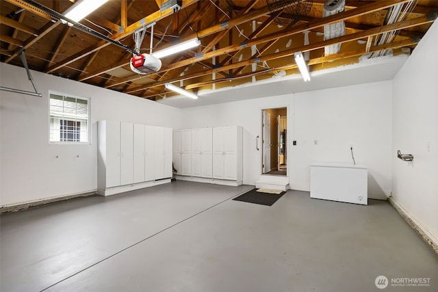 garage featuring a garage door opener, baseboards, and fridge