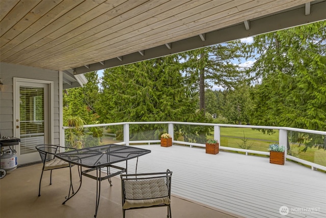 wooden terrace with view of scattered trees and outdoor dining space